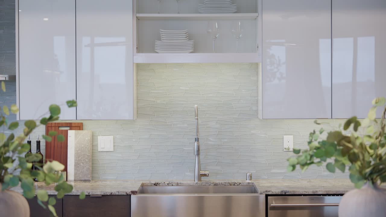 Pedestal shot of a bright modern kitchen faucet and sink with granite counters and decorative vases