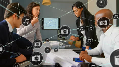 Animation-of-network-of-connections-with-icons-over-diverse-business-people-in-office