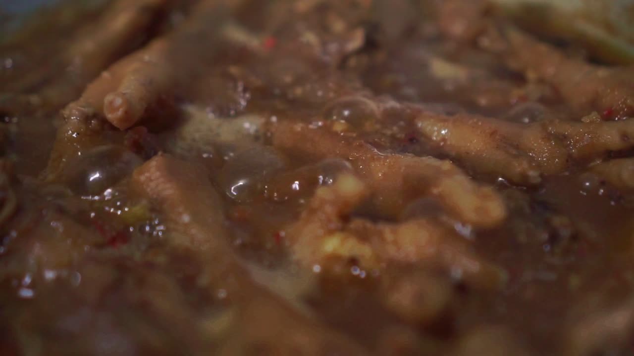 Carne di pollo che cuoce in un sugo denso e bollente. Macro di un delizioso piatto di pollame che sobbolle con spezie.