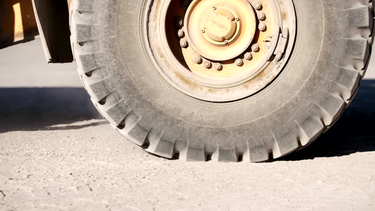 un primer plano de una enorme rueda amarilla de un cargador moviéndose hacia adelante