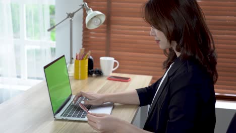 las mujeres de negocios están pagando con tarjetas de crédito para comprar con computadoras portátiles de pantalla verde concepto inalámbrico compras en línea.