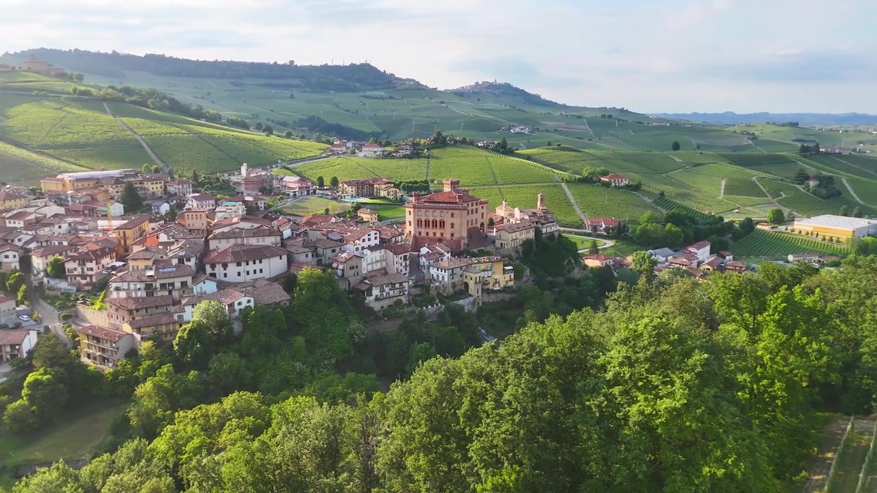 Ampia ripresa aerea con drone panoramica su un borgo storico italiano circondato da dolci colline vitate