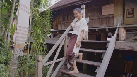 girl in thai traditional dress walking down stair's thai house, slow motion