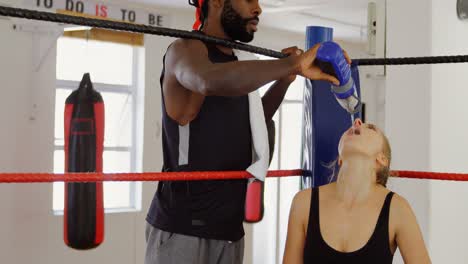 Male-trainer-feeding-water-to-female-boxer-in-boxing-ring-4k