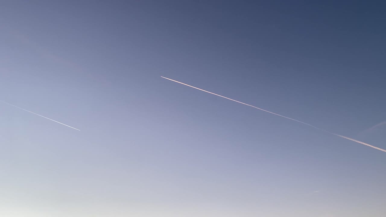 Aviões de carreira voam deixando rastros brancos no céu.