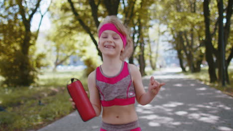 Sport-runner-jogger-child-girl-listen-bluetooth-music-speaker-dancing-having-fun-walking-in-park