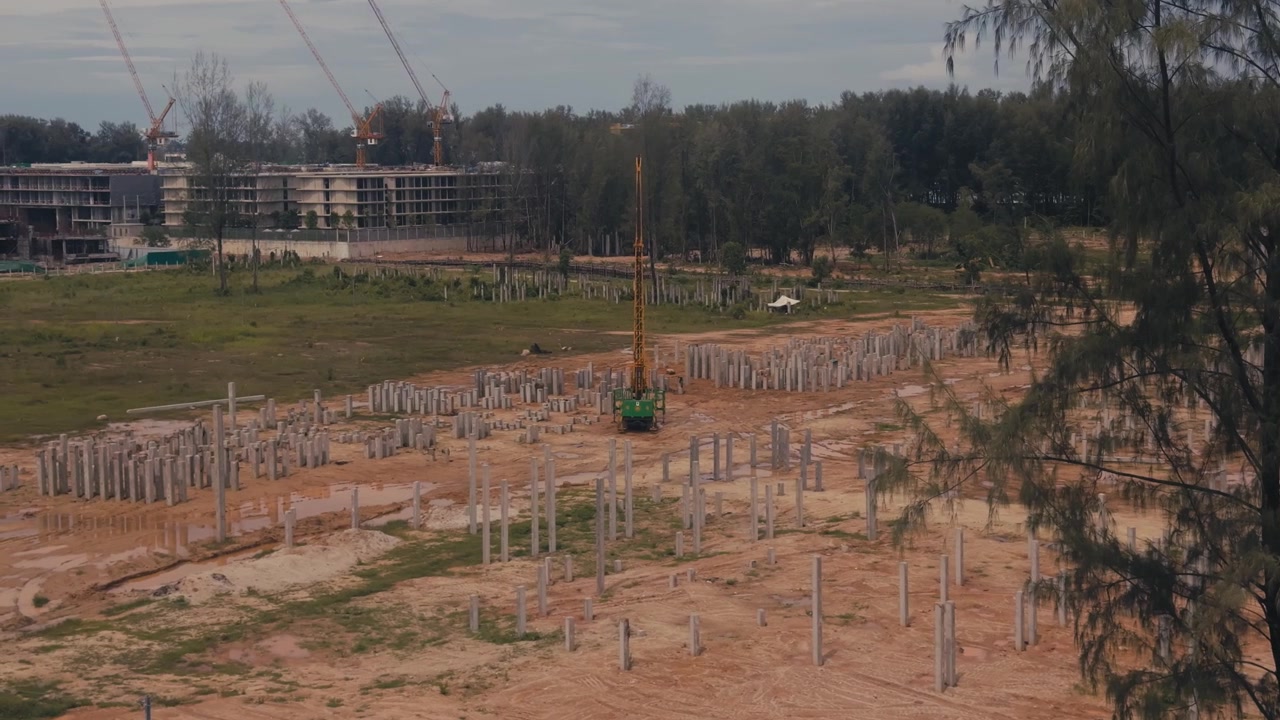 Aktive Baustelle mit im Boden verankerten Betonfundamentpfählen, Hochhäusern und Kränen im Hintergrund, die den Fortschritt der Stadtentwicklung zeigt