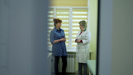 doctor talking with elderly woman. doctor talking to patient in hospital, behind the door