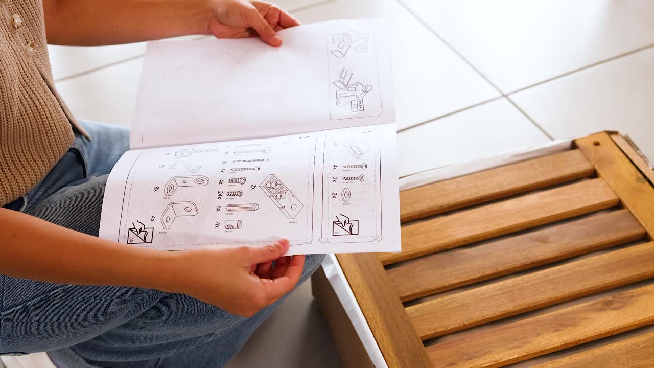 A person examines detailed assembly instructions for a wooden furniture piece in a well-lit indoor setting