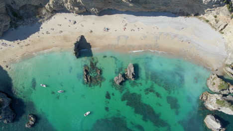 Luftaufnahme-Von-Oben-Auf-Den-Strand-Mit-Türkisfarbenem-Wasser-Und-Den-Klippen-Von-Ribeiro-Do-Cavalo,-Sesimbra