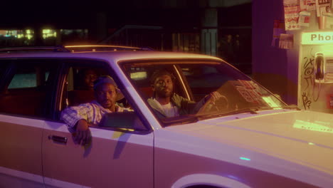 group of african american friends posing in car under overpass at night