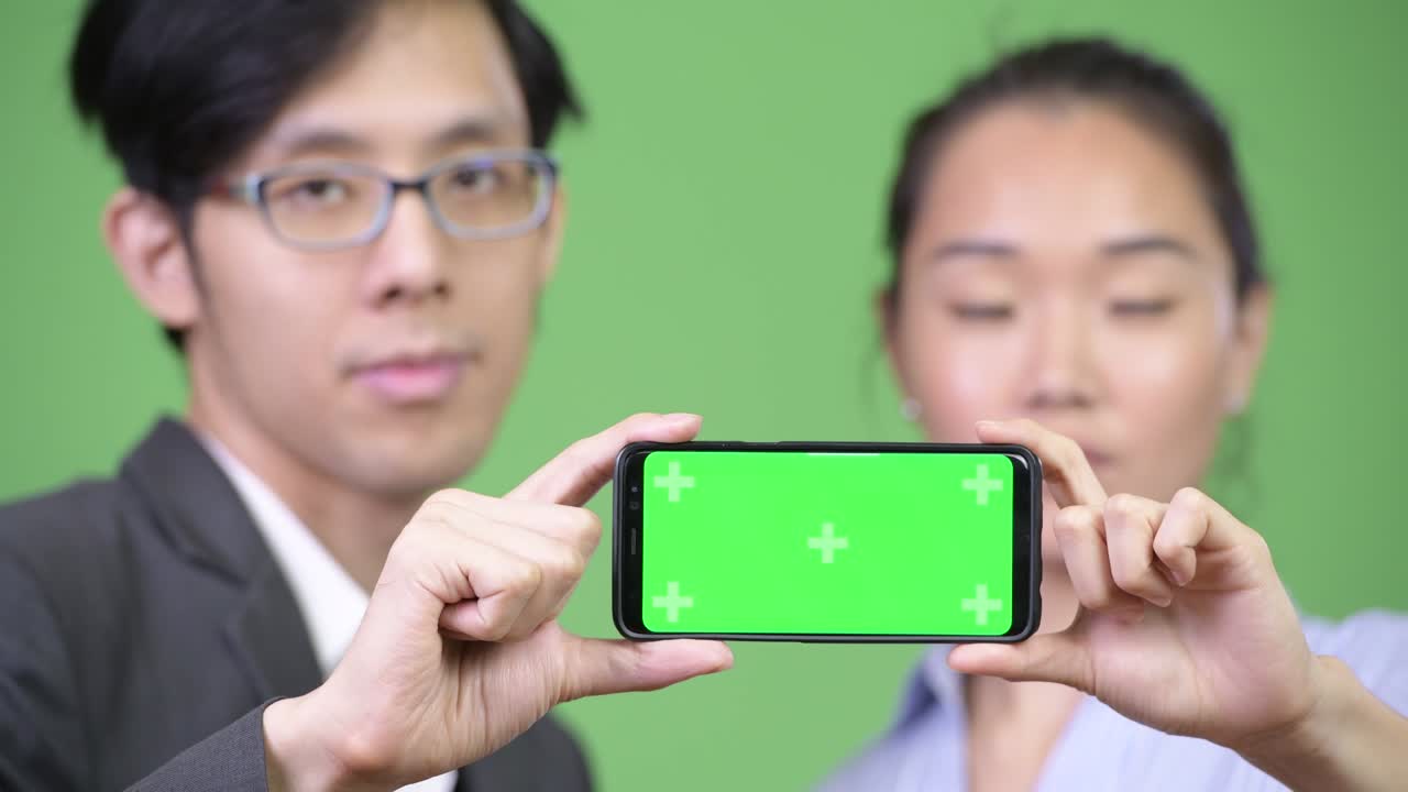Young Asian business couple showing phone together