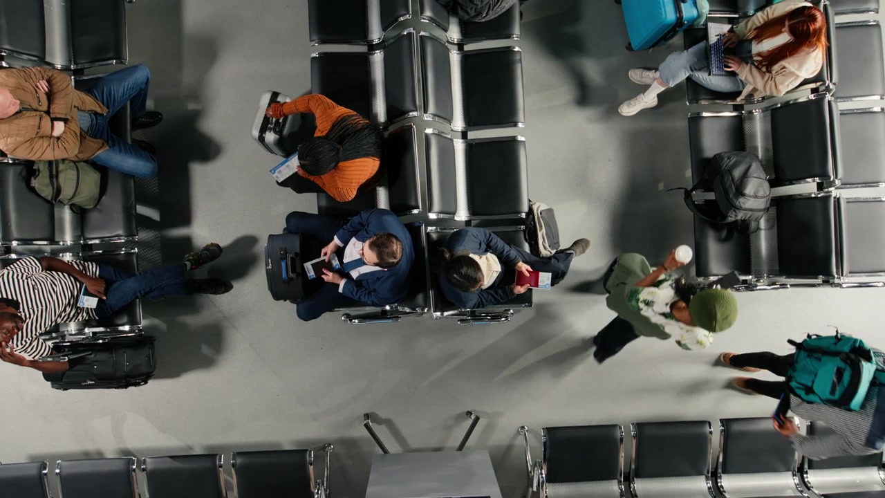 Walking, devices and travelers in airport terminal next to people on chairs