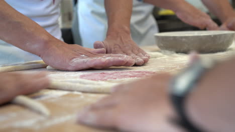 human hands making pasta on a wood table with fingering and dexterity