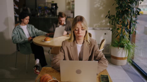 mujer trabajando en una computadora portátil en una cafetería