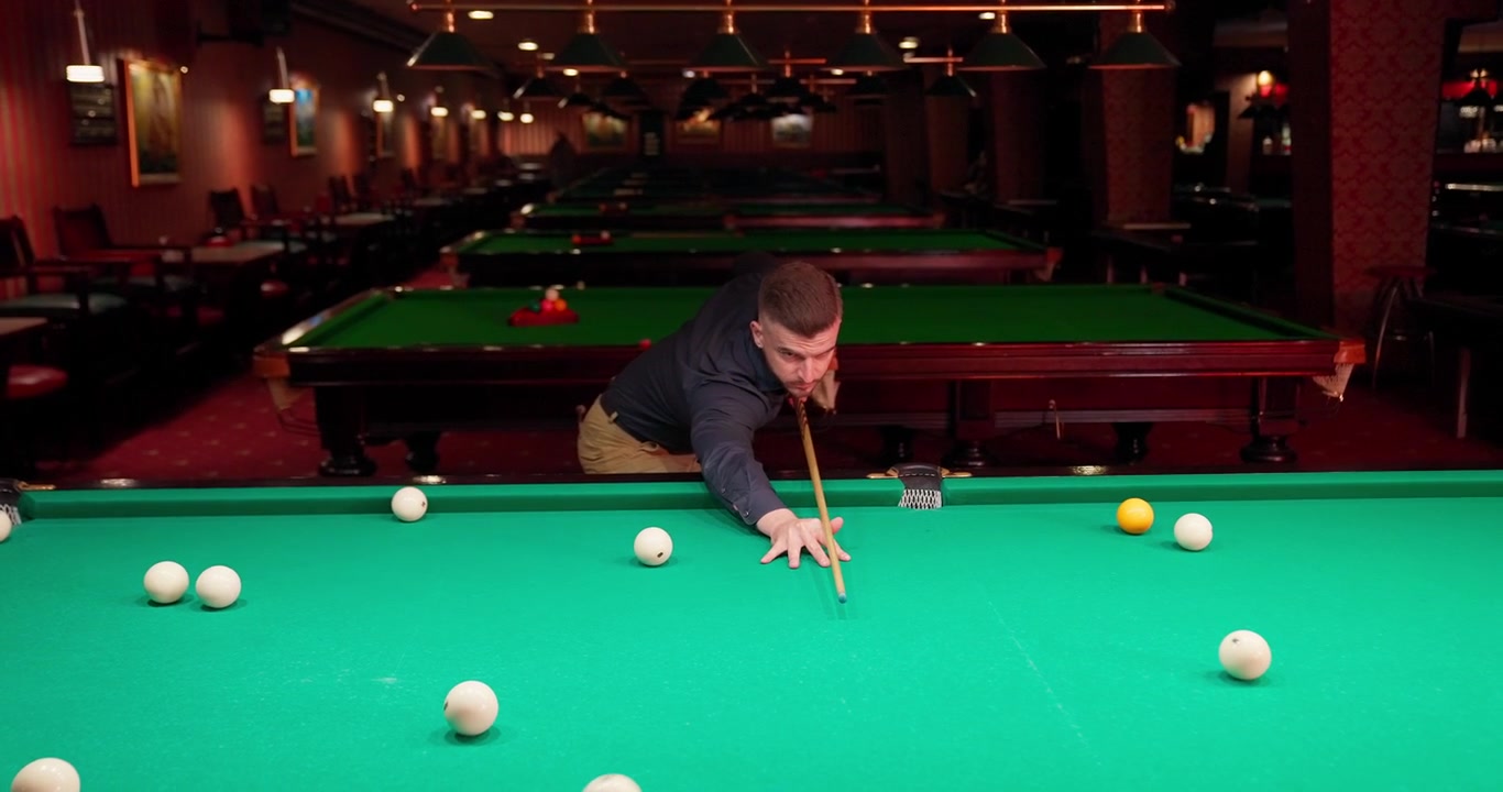 Man speelt biljart en neemt een stoot in een poolhal