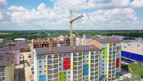 Construction site of a modern district. Tower crane build new high-rise buildings on nature background. Residential complex is building. Drone view.