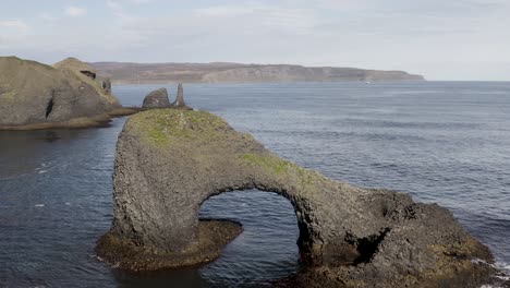 aerial approaching shot of raudanes sea stacks on coastline of iceland during sunny day - flyover drone shot