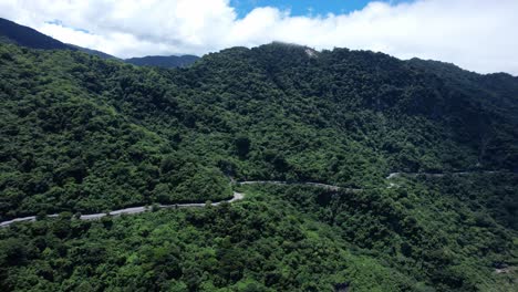 Pivoting-with-slow-orbit-to-reveal-tropical-beach-next-to-lush-cliff-side-highway-in-Eastern-Taiwan