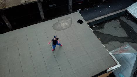 overhead aerial drone shot of a young adult male parkour free runner practicing on an abandoned roof top