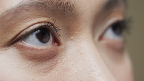 ojos de una mujer asiática con cabello oscuro sobre un fondo beige, cámara lenta
