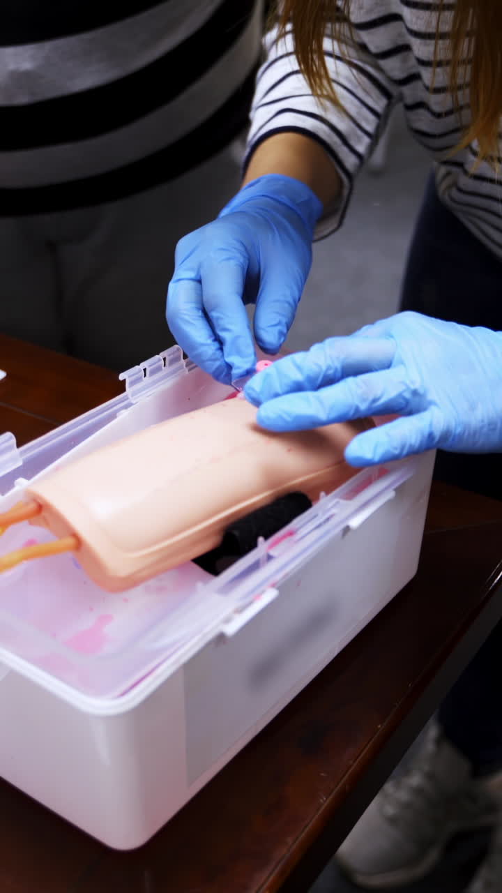 Training injection into a vein on a mannequin arm. Student studying how to put dropper in a training center. Medical practice. Vertical video
