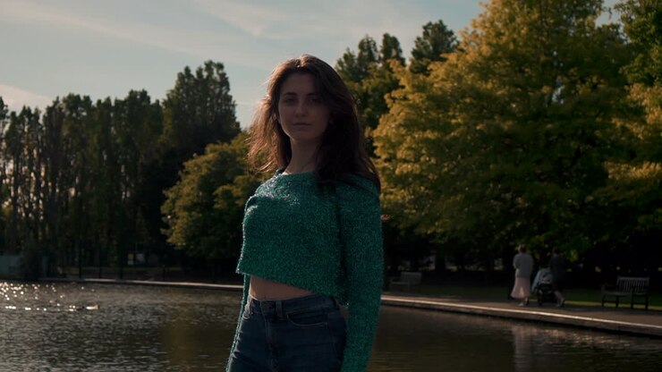 Gorgeous Italian fashion model posing in her outfit in front of a lake in London at golden hour
