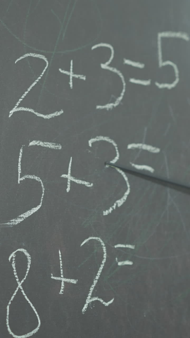 el maestro muestra tareas de matemáticas escritas en la pizarra con un puntero en primer plano en el aula. problemas matemáticos simples para estudiantes de escuela primaria en la pizara