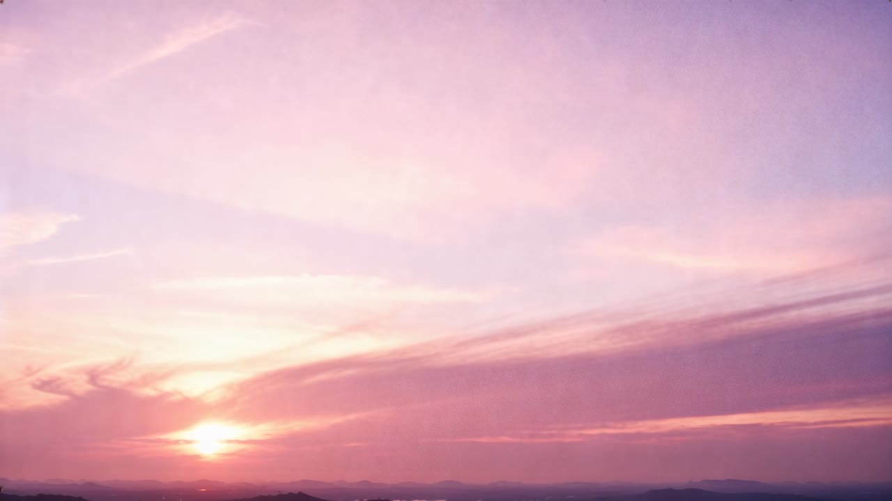 Light spreading across clouds revealing sun lifting over low coastal horizon, reflecting on water