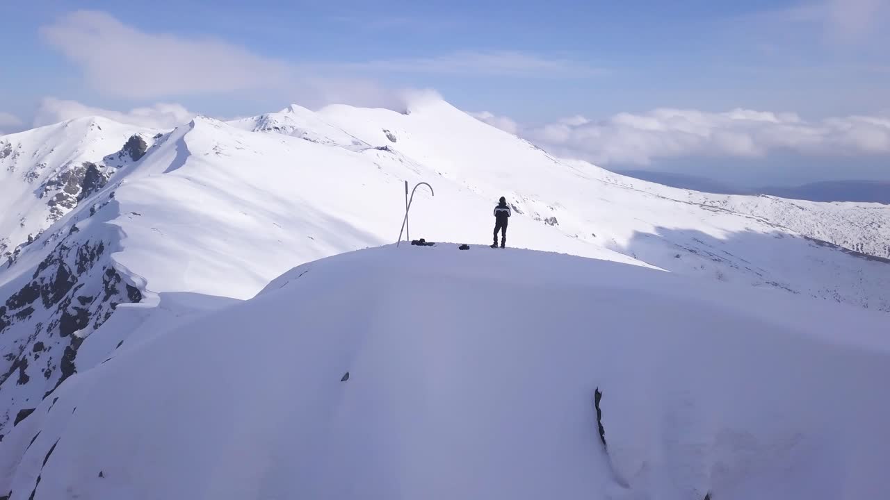 Uomo in piedi su una cima montuosa innevata.