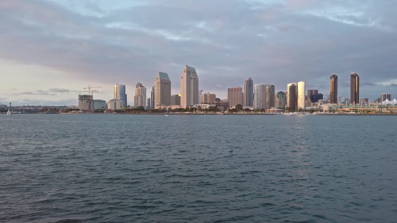 San Diego Convention Center and downtown view from a boat on local bay. Cloudy purple sky. Distance shot