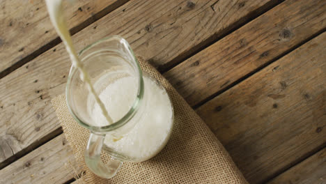 video of glass jug of milk on wooden background