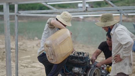 workers repairing a diesel engine near a reservoir