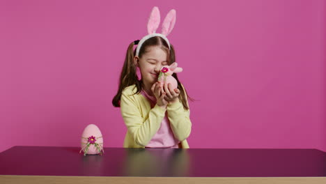 smiling toddler with bunny ears showing her handmade easter ornaments