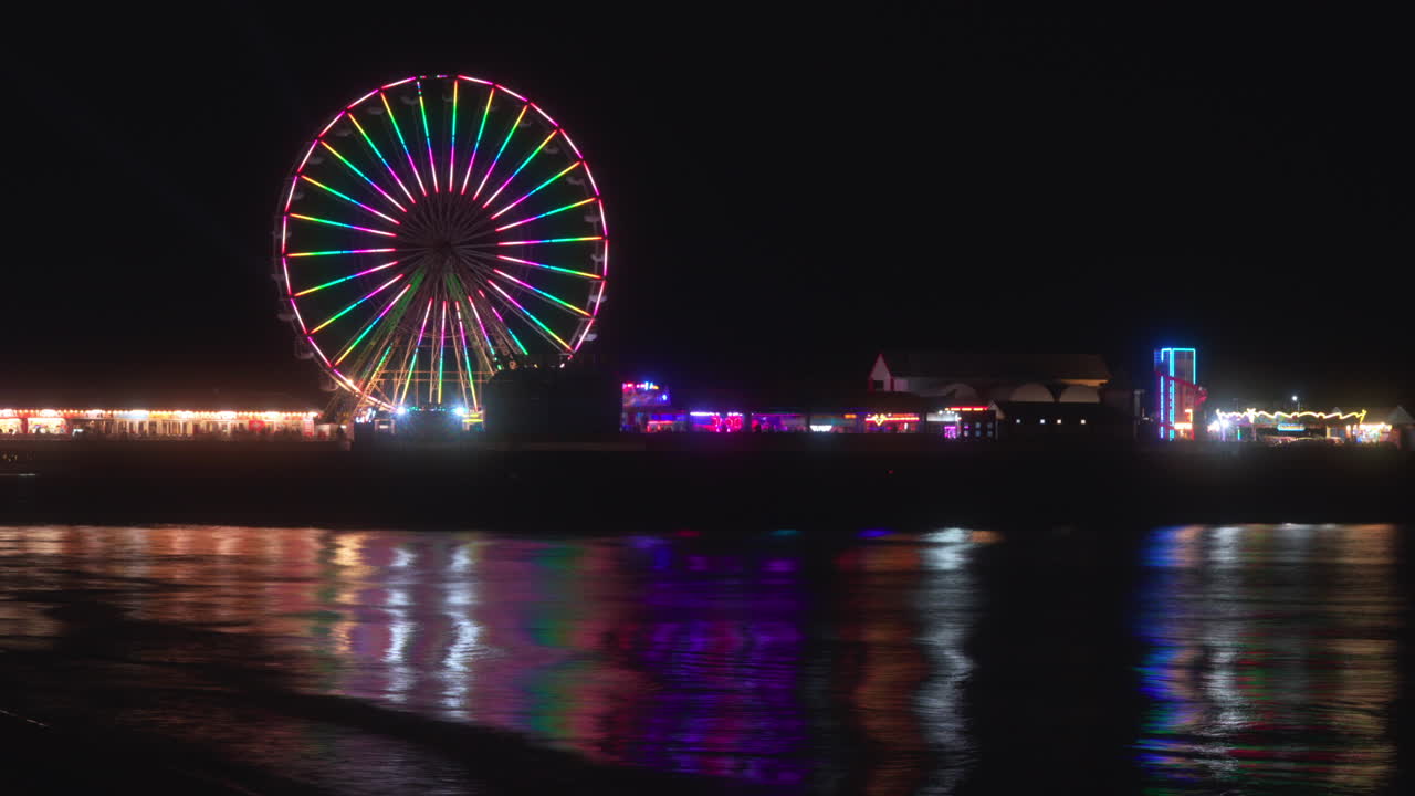gran paseo en rueda y diversiones por la noche con luces que se reflejan de la marea entrante en el muelle central, blackpool, lancashire, inglaterra, reino unido
