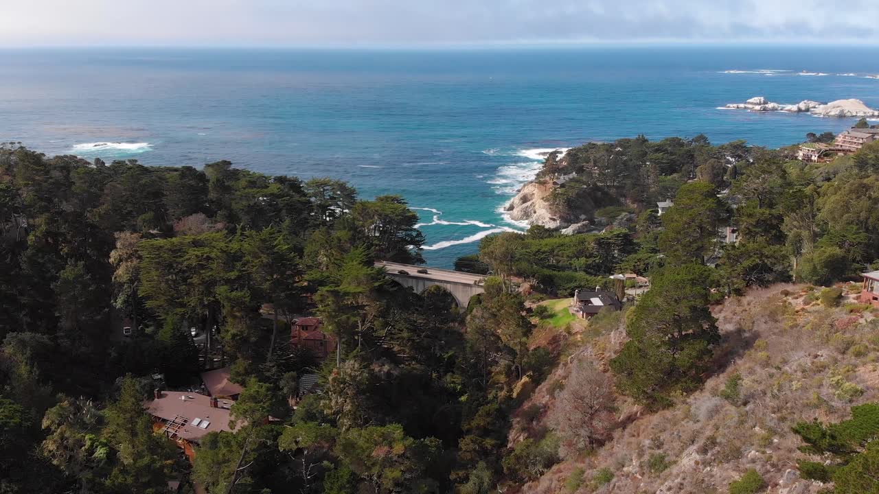 카멜 바이 더 씨 빅서 인근 다리 근처의 해안 협곡 주택 옆을 지나가는 자동차