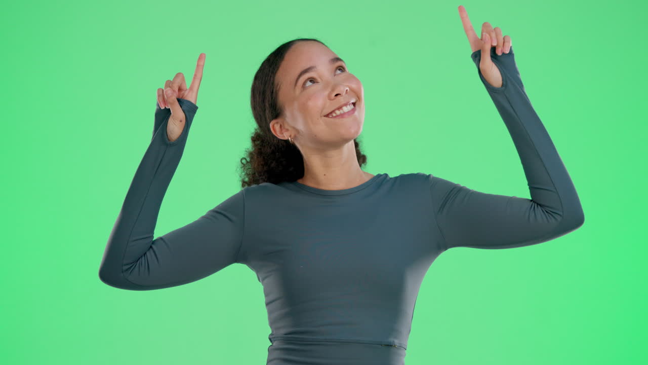 Woman pointing upwards on green screen