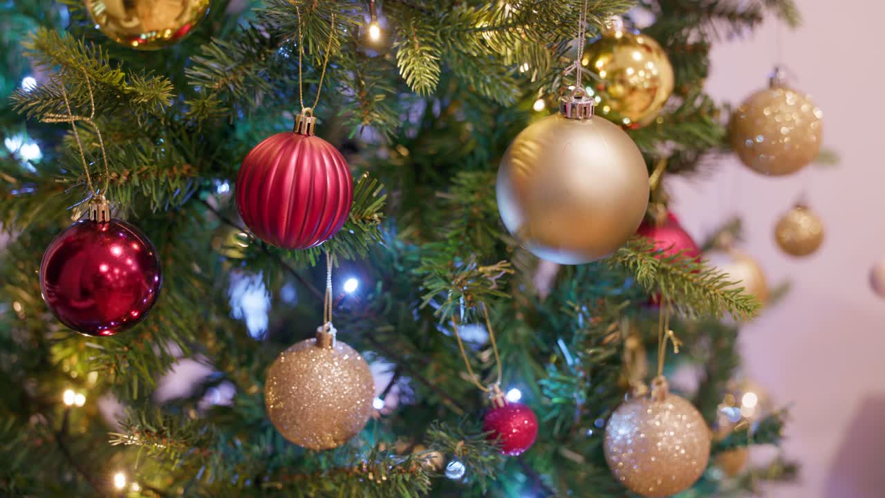 A festive shot of red and gold ornaments glowing under Christmas tree lights, perfect for holiday visuals.