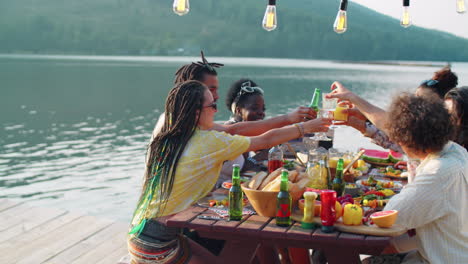 multiethnic friends toasting at dinner party on pier