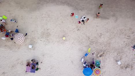 Toma-Aérea-De-Familias-Con-Niños-Y-Sombrillas-Disfrutando-De-La-Playa-Bombas-En-Brasil