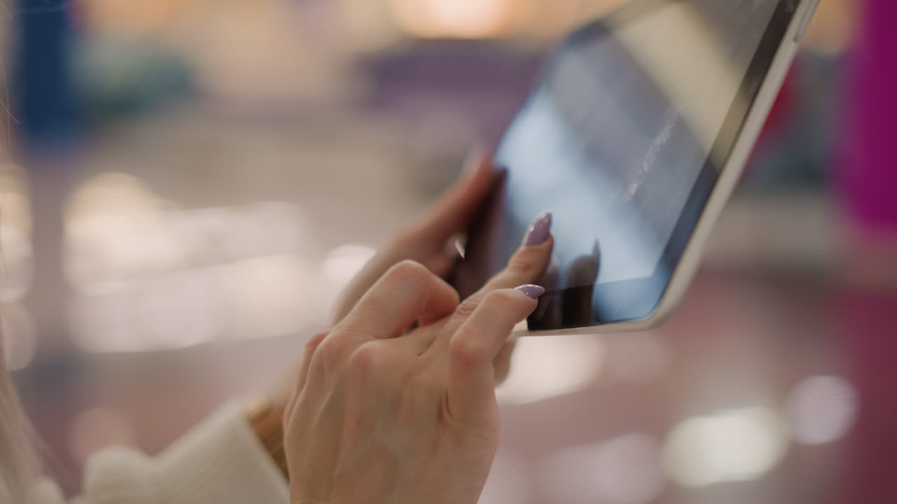 close up demure hands with long lavender nails tapping glossy tablet screen, subtle reflection of fingers, focus shopping mall floor backdrop conveying refined digital interaction and elegance