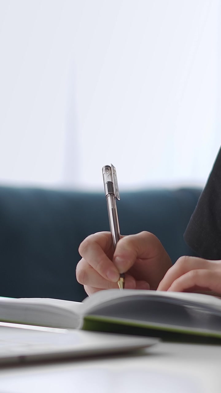 Close-up of Person Writing in Notebook with Pen