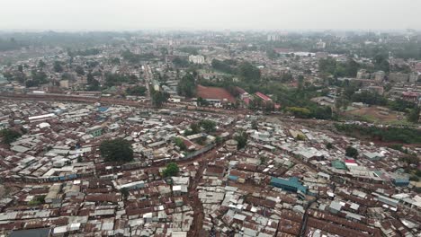 Luftaufnahme-Des-Armenviertels-Kibera-Slum-Nachbarschaft-Von-Nairobi,-Kenia-Und-Nebliger-Skyline,-Drohnenschuss-Zurückziehen