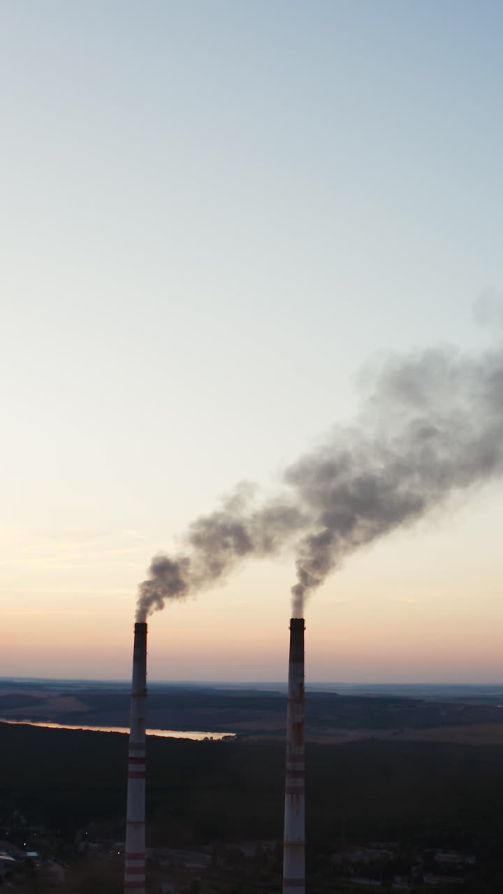 Smoke pipes of factory. Factory with chimneys expelling smoke into deep blue sky Vertical video