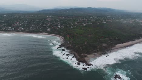 Drone-ascends-pulling-back-to-reveal-homes-and-town-around-Puerto-Escondido-Oaxaca-Mexico-on-stormy-day