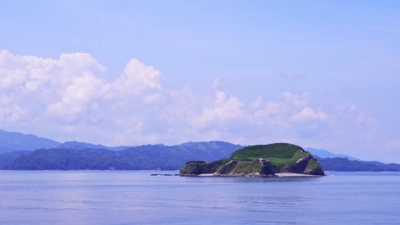 Passing Island with Mountains on the Horizon in Costa Rican Landscape on Sunny Day with cloudy Sky, Full Shot