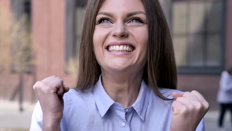 young woman celebrating success outside office