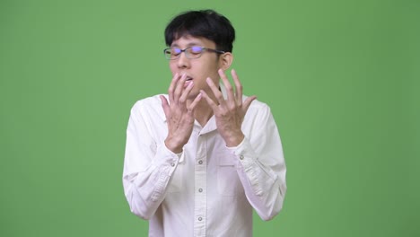young asian businessman shocked while covering mouth