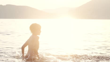 happy child swims in the sea at sunset. joyful boy has fun and splashes with water while swimming in the lake. active leisure during school holidays