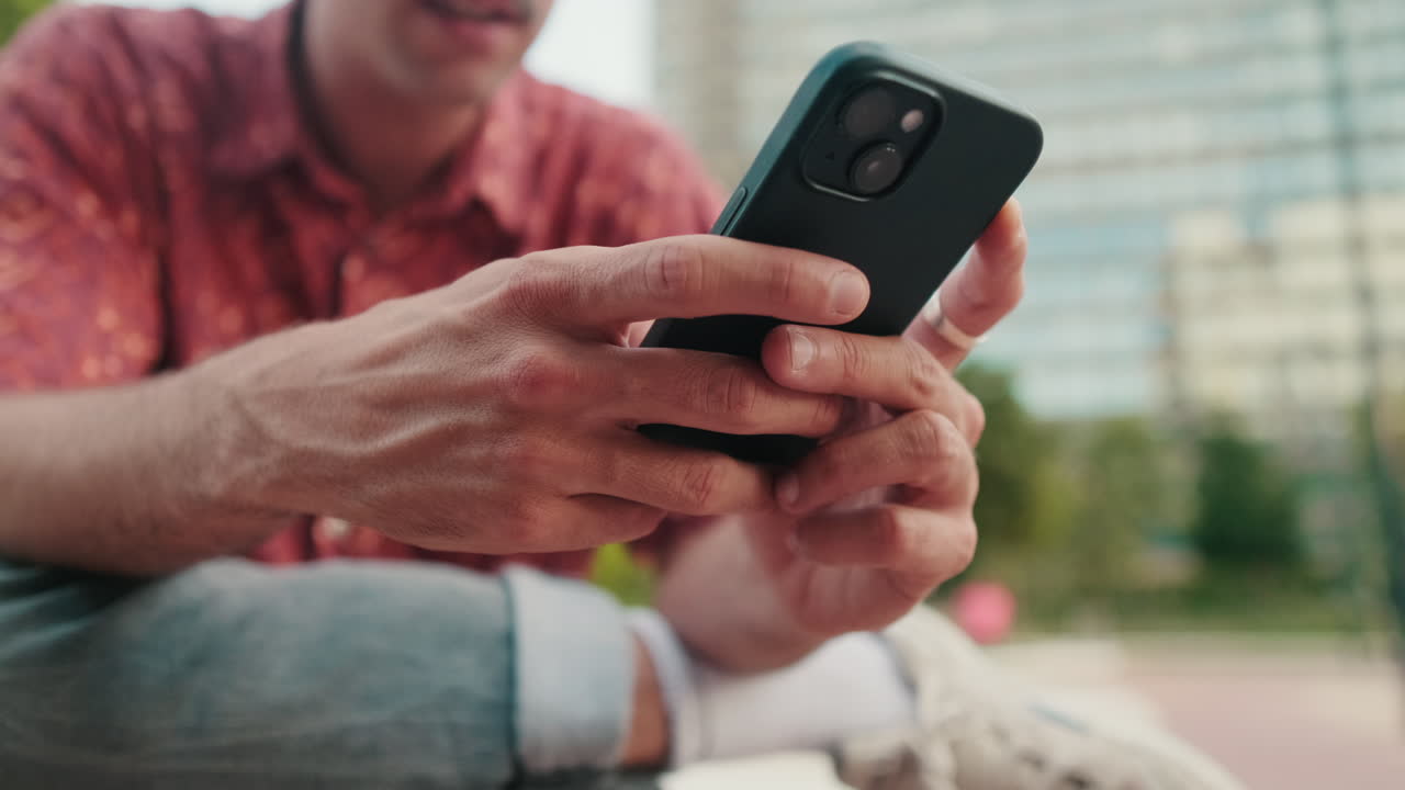 Close-up of Man's Hands Using a Smartphone Outdoors
